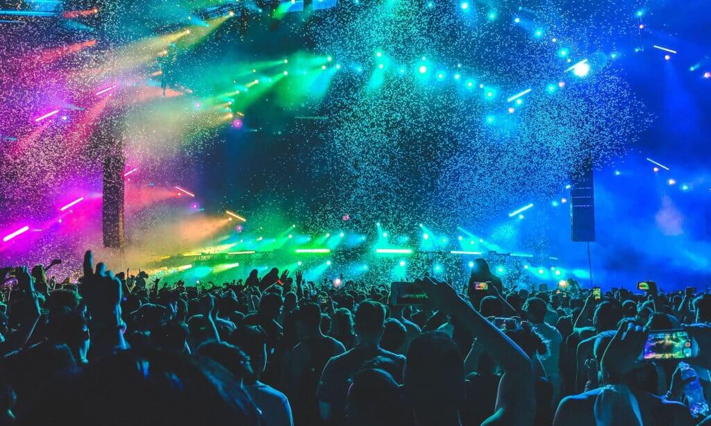 fans dancing at a concert with colorful lights