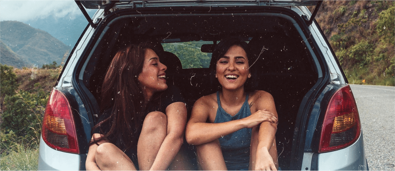 two girls laughing in the back of a car while traveling