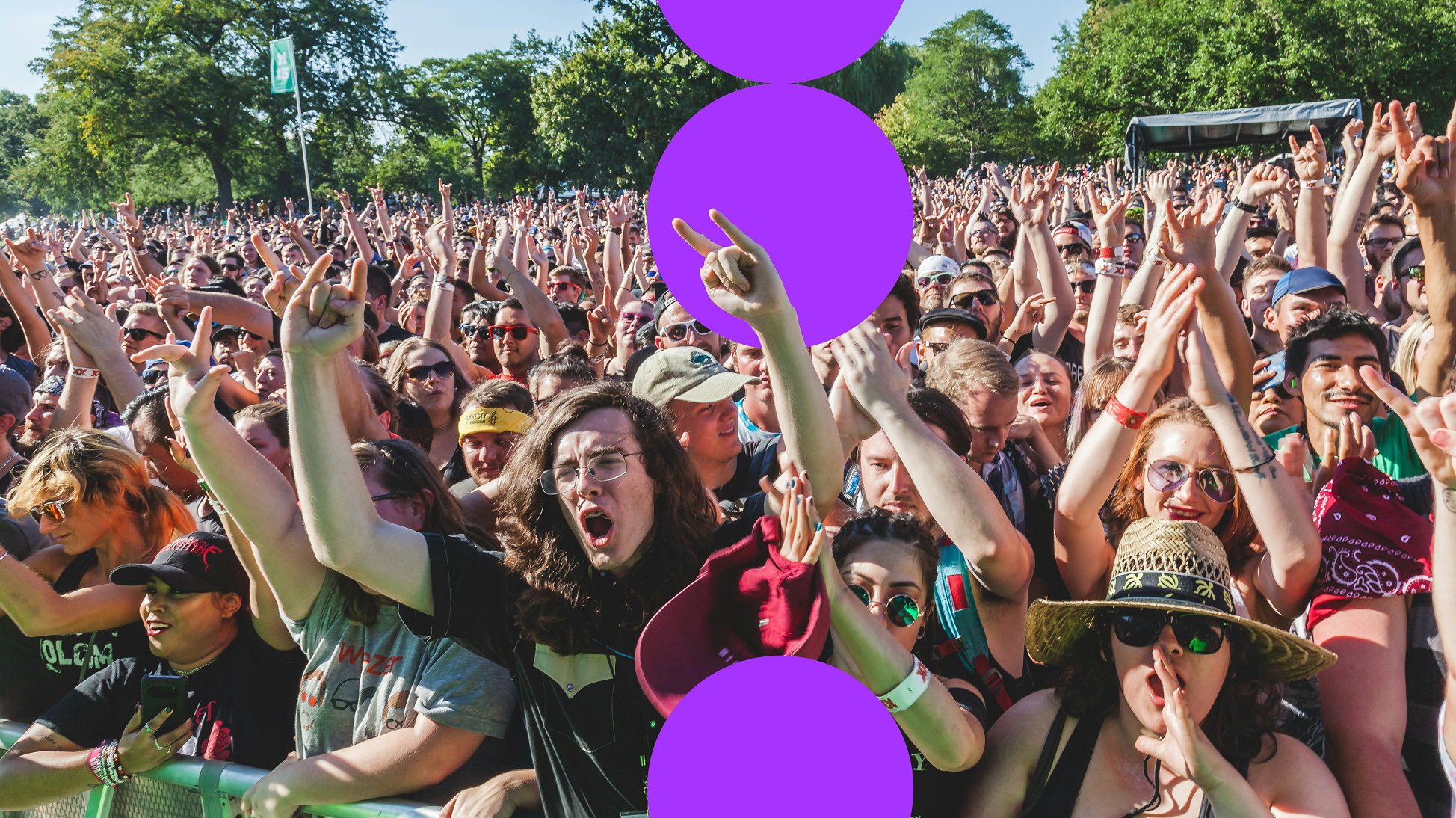 A crowd of people at a music festival with their hands in the air.